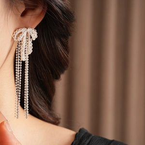 Macro shot of silver bow tassel earrings with sparkling cubic zirconia on a model