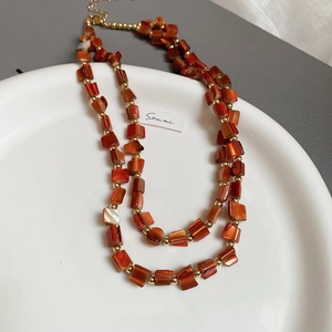 Detail of beaded necklace with orange shell fragments and gold lobster clasp closure