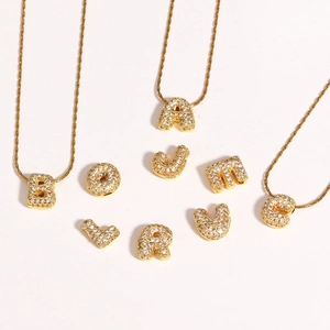 Colliers pendentifs lettres dorées avec micro-pavé de zircone sur fond beige