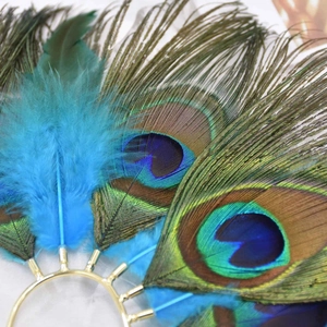 Macro shot of natural peacock feathers and gold metal base of the vintage ear cuff