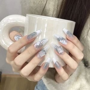 Detail of handmade cat-eye press-on nails with blue marble texture and white flowers