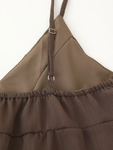 Detail of adjustable strap with metal buckle on sequined brown beaded dress fabric