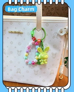Detail of green acrylic rabbit charm with colorful beads on a white tote bag
