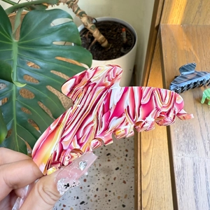 Macro detail of large marble pattern hair claw clip with red and yellow textures