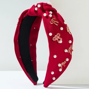 Close-up of red fabric knotted headband with white pearls and enamel bow detail