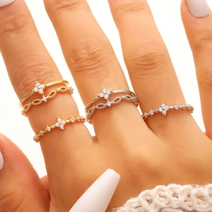 Detail of layered gold and silver rings with cubic zirconia cross petals and textured bands