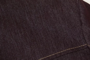 Gros plan sur la texture du tissu sombre avec des coutures décoratives dorées contrastées
