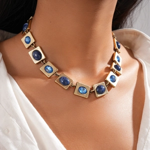Detail einer Vintage-Halskette in Goldoptik mit blauen Harzsteinen am Modelhals