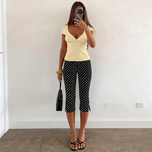 Détail d'un pantalon moulant noir à pois blancs avec un haut jaune à col en V élégant