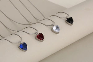 Detail view of heart-shaped crystal pendant necklaces in various colors on snake chain