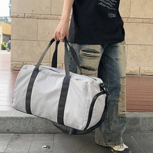 Gray waterproof nylon gym bag with black straps held by model in outdoor street setting