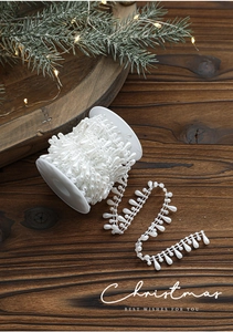 Close-up of white teardrop pearl beaded ribbon on spool for Christmas DIY crafts