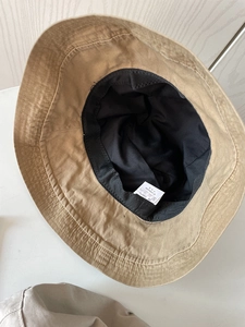 Detail view of khaki cotton bucket hat interior featuring black sweatband and 100% cotton label