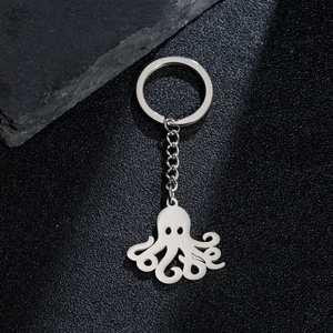 Polished stainless steel octopus pendant keychain on a dark textured rock surface