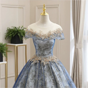 Detail of light blue evening gown featuring gold floral embroidery and sequins on mesh fabric