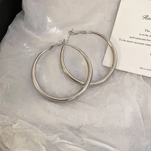 Macro shot of silver round hoop earrings on white tissue paper with decorative card