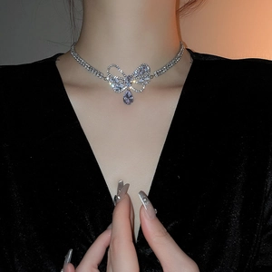 Close-up of a silver bow necklace with a teardrop zircon pendant worn by a model