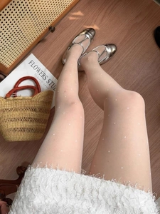Detailed view of white polka dot sheer pantyhose worn with silver Mary Jane shoes
