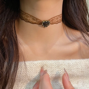 Detail of vintage brown lace choker necklace with heart charm and pearl accents on model
