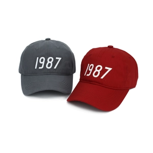 Detail of 1987 embroidery on dark grey and deep red cotton twill baseball caps