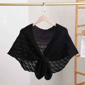 Detail view of a black knitted hollow-out shawl wrap hanging on a wooden hanger