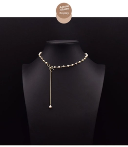 Detail of pearl necklace with gold bow pendant and long tassel drop on mannequin