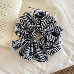 Oversized black and white gingham scrunchie with light blue trim on a vintage book