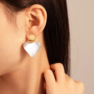Minimalist two-tone geometric heart earrings in gold and silver finish on model
