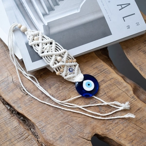 Detail of bohemian evil eye wall hanging with cream woven rope and blue glass beads