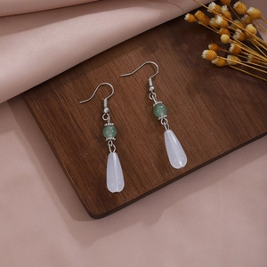 Detailed macro view of Chinese style butterfly pearl tassel earrings on dark wood