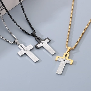 Detailed close-up of two-tone stainless steel cross pendants with engraved scripture text