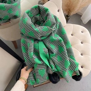 Women's houndstooth cashmere scarf with green hearts and black pompoms on a chair