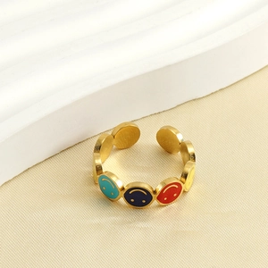 Close-up of golden stainless steel open ring with colorful enamel smiley face patterns