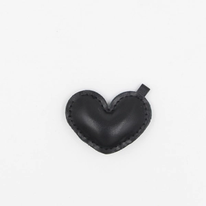 Detail shot of heart-shaped black leather charm with premium stitched edges and soft texture