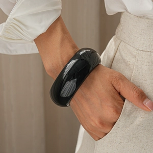 Close-up of polished black resin geometric bangle on model's wrist with minimalist aesthetic
