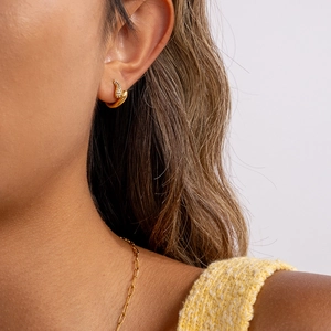 Détail d'un mannequin portant une boucle d'oreille C en or avec zircons et sa chaîne