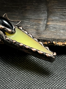 Macro shot of vintage bronze pendant featuring black agate and translucent green stone