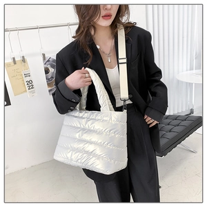 Detail of silver quilted padded tote bag with metallic finish and wide shoulder strap
