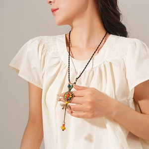 Close-up of Bohemian ethnic long necklace with ceramic beads and leaf metal pendants