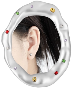 Macro shot of silver heart earrings reflected in a wave mirror with multi-color gems