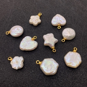 Macro shot of assorted pearl charms in star and heart shapes with gold metal loops