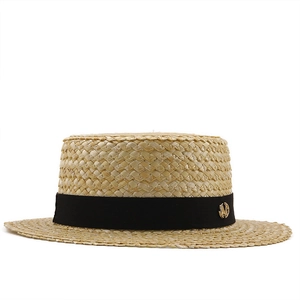 Détail d'un chapeau de paille de blé avec ruban gros-grain noir et badge doré chic
