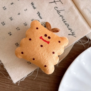 Macro detail of plush cookie pendant featuring cute facial expression and metal bead chain