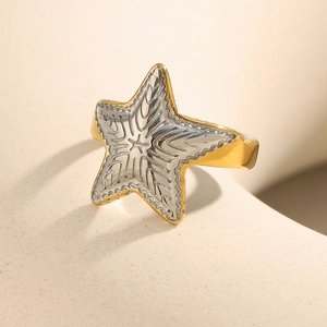 Detail of starfish ring in gold and silver finish with engraved textured relief