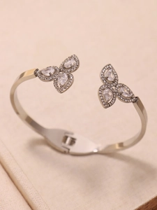 Macro shot of silver-tone clover bangle with 5A pear-cut zircons on beige fabric