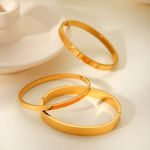Detail of three gold-plated stainless steel bangles with polished mirror finish