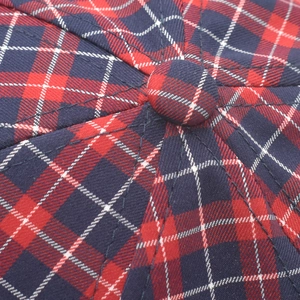 Macro shot of red and navy plaid fabric texture with central button on baseball cap