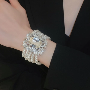 Detail of a multi-layer pearl bracelet with a large square gemstone and zircon settings