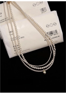 Macro view of multi-layer freshwater pearl necklace with a polished gold heart pendant