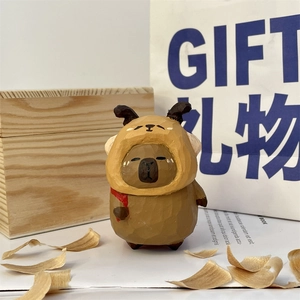 Hand-carved wooden capybara figurine wearing a brown hoodie with a gift bag setup